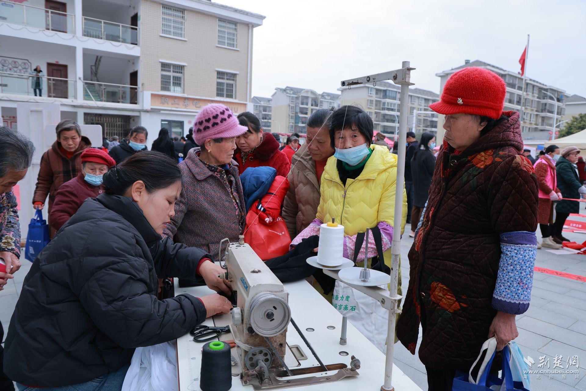 衣物縫補(bǔ)攤前，志愿者飛針走線為居民修補(bǔ)破損衣物.jpg.jpg